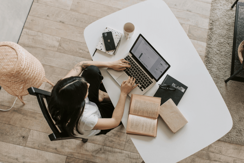 a woman sitting at the table produces seo texts on the laptop
