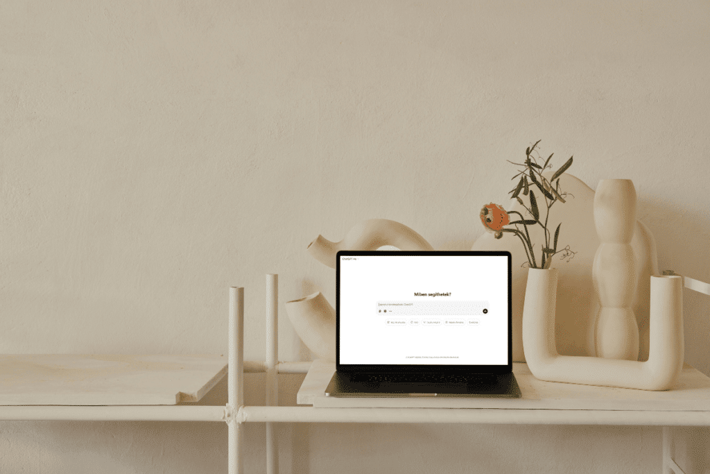 fekete laptop egy fehér polcon, amelyen a ChatGPT keresési felülete látható.